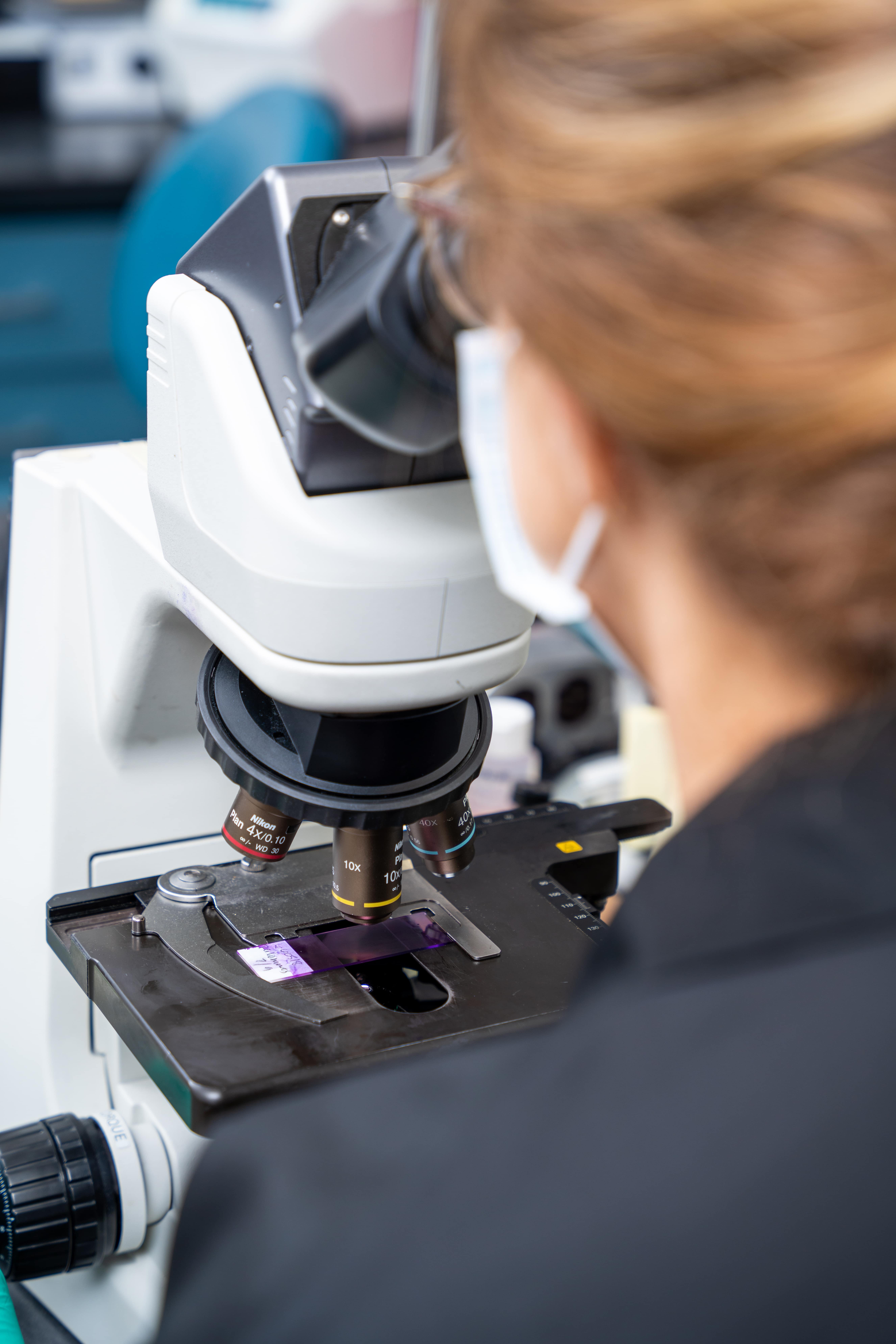 woman looking into microscope